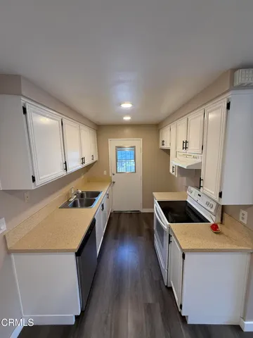 a kitchen with granite countertop a sink stove and cabinets