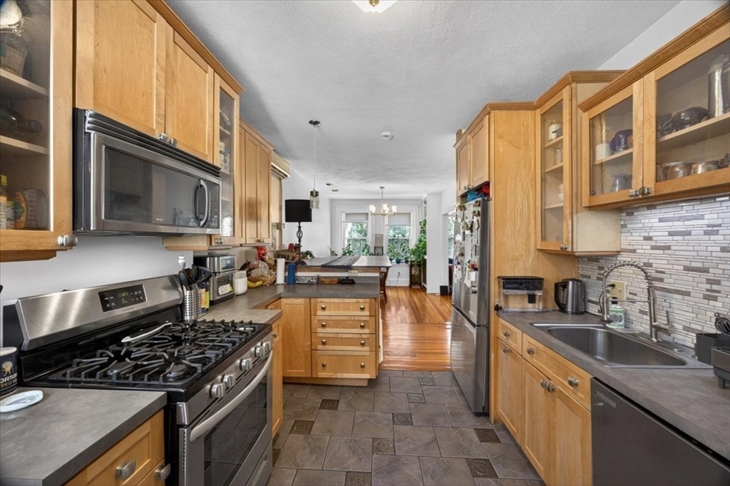 23 Netherlands Road, Unit 1 Brookline, MA 02445 - Photo 1 of 35 a kitchen with stainless steel appliances granite countertop a stove top oven a sink a dining table and chairs