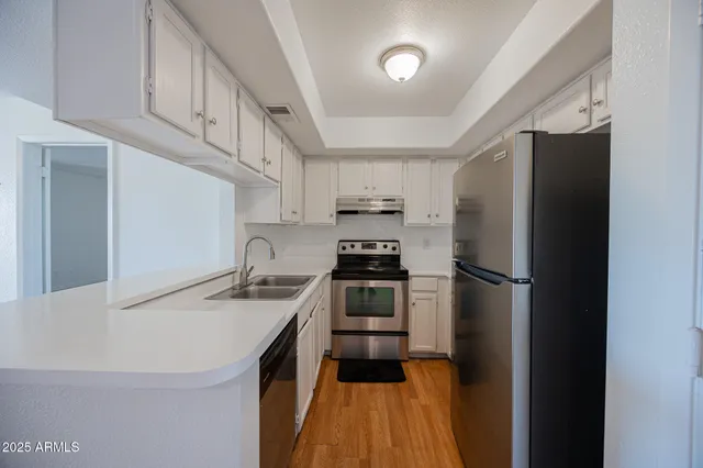 a kitchen with stainless steel appliances a refrigerator a sink a stove and white cabinets