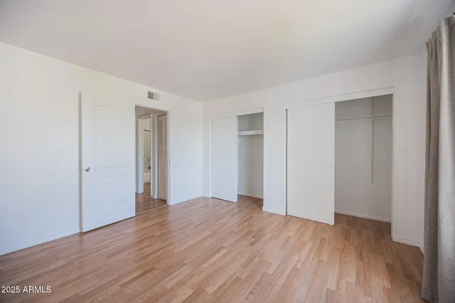 a view of an empty room with wooden floor and closet
