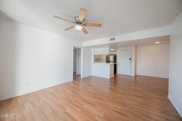 a view of empty room with wooden floor and ceiling fan