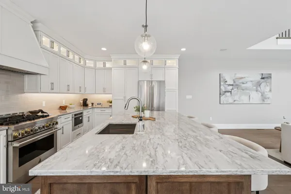 a large kitchen with stainless steel appliances granite countertop a stove a sink dishwasher and a refrigerator with wooden floor