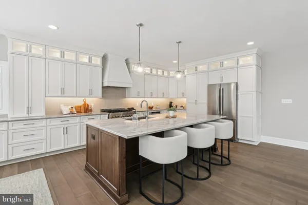 a kitchen with a sink a refrigerator a stove a dining table and chairs with wooden floor