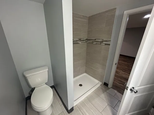 a bathroom with a granite countertop toilet and a shower