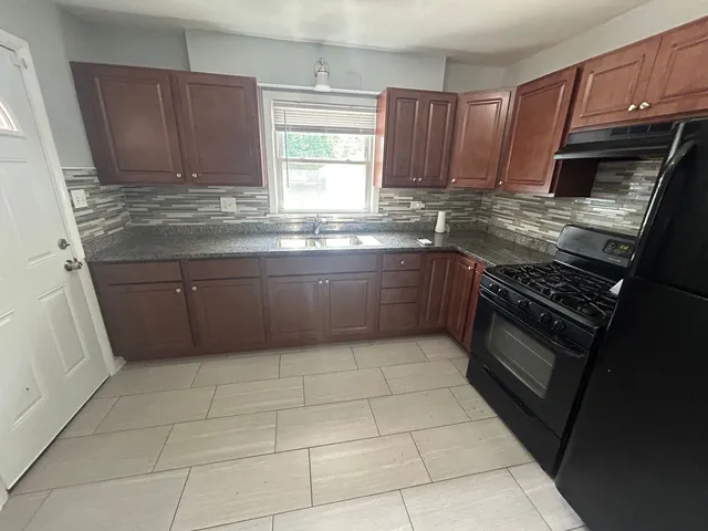 a kitchen with granite countertop a stove a sink and a microwave
