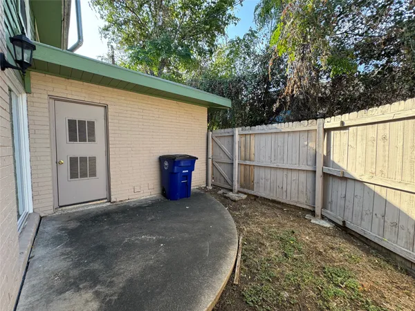 a view of a backyard with wooden fence and large trees