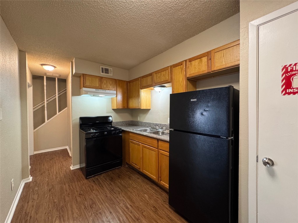 4904 West Wind Trail, Unit 103 Austin, TX 78745 - Photo 7 of 22 a kitchen with a refrigerator and a stove top oven