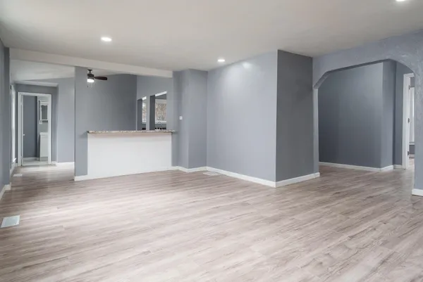 a view of empty room with wooden floor and fan