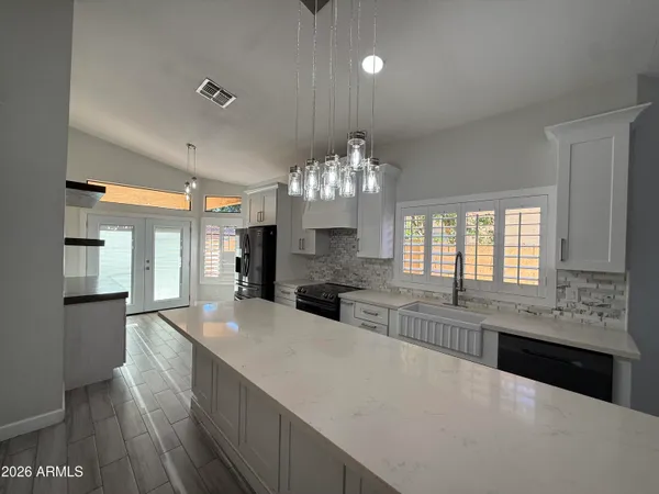 a large kitchen with granite countertop a large counter top a sink stainless steel appliances and cabinets