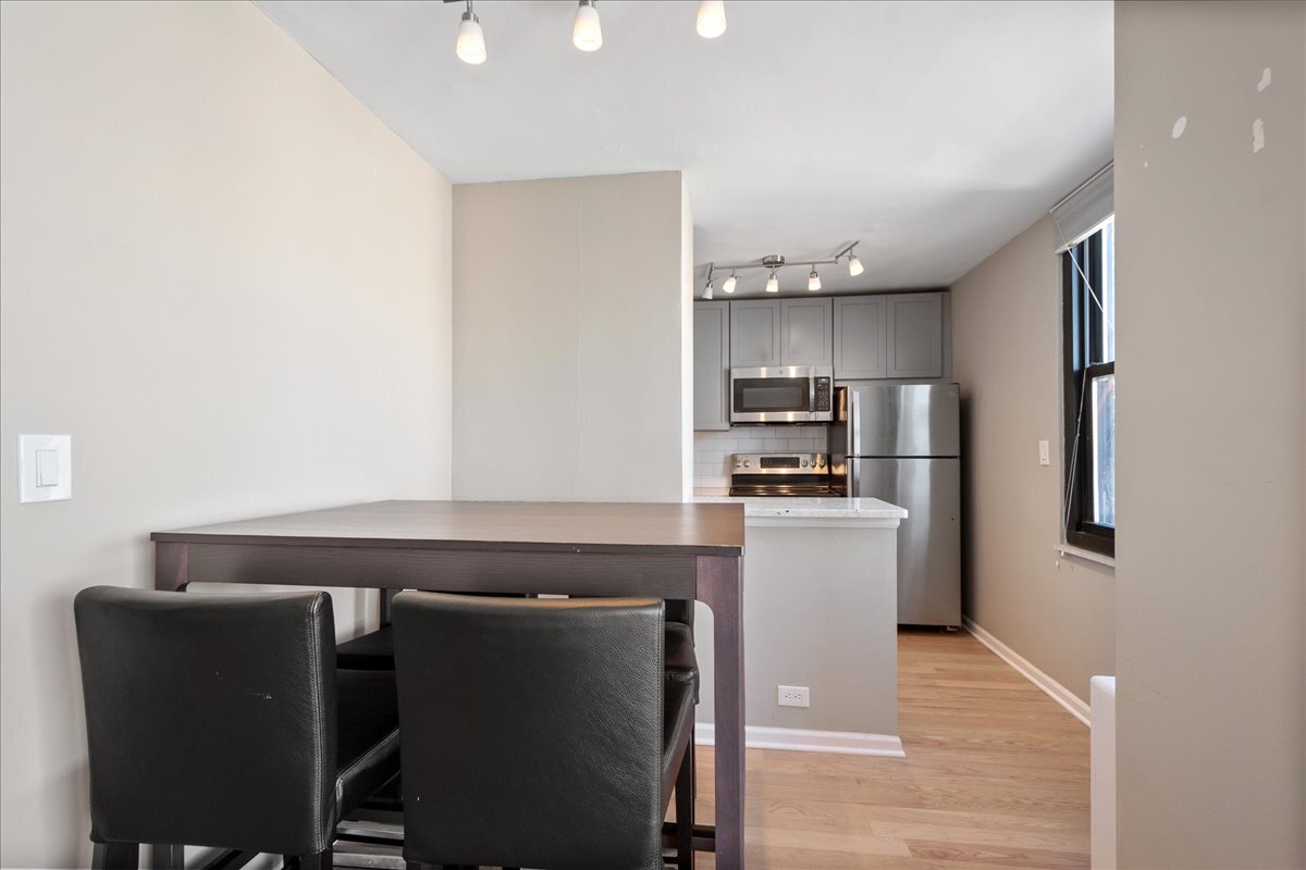 5701 North Sheridan Road, Unit 29N Chicago, IL 60660 - Photo 9 of 19 a kitchen with kitchen island a sink cabinets and wooden floor