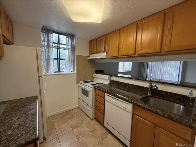 a kitchen with granite countertop cabinets stainless steel appliances a sink and a window