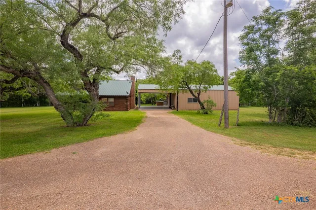 a view of a house with a big yard and large trees