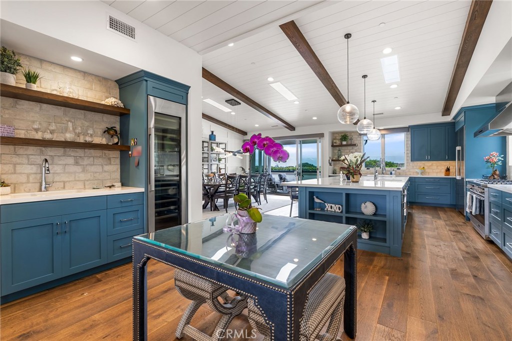 1231 Sand Key Corona del Mar, CA 92625 - Photo 28 of 65 a kitchen with stainless steel appliances granite countertop a kitchen island a stove a table and chairs with wooden floor