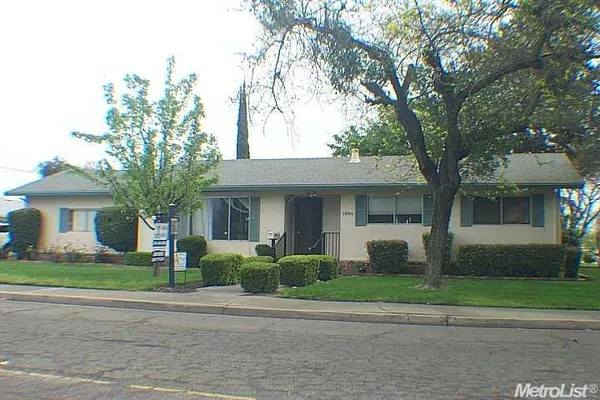 a front view of a house with a garden and trees