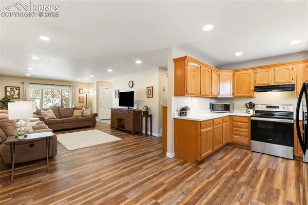 a kitchen with stainless steel appliances granite countertop a stove top oven a sink dishwasher and a refrigerator with wooden floor