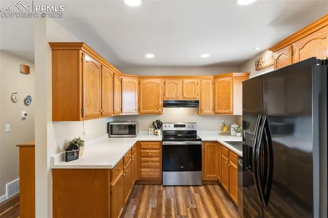 a kitchen with stainless steel appliances granite countertop a refrigerator a stove top oven a sink and dishwasher