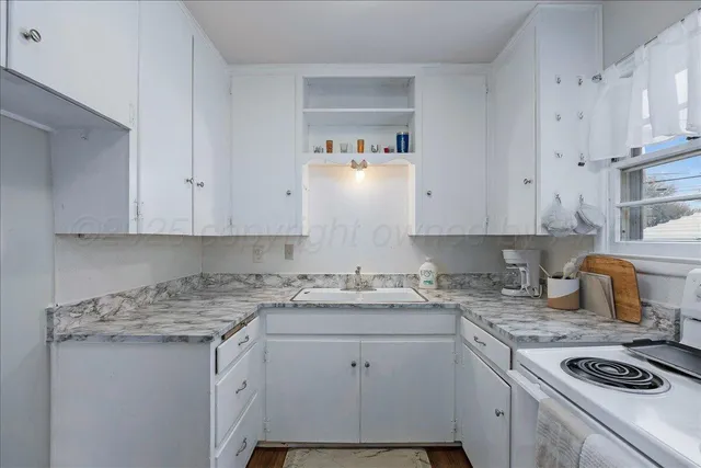 a kitchen with granite countertop a sink a stove and cabinets