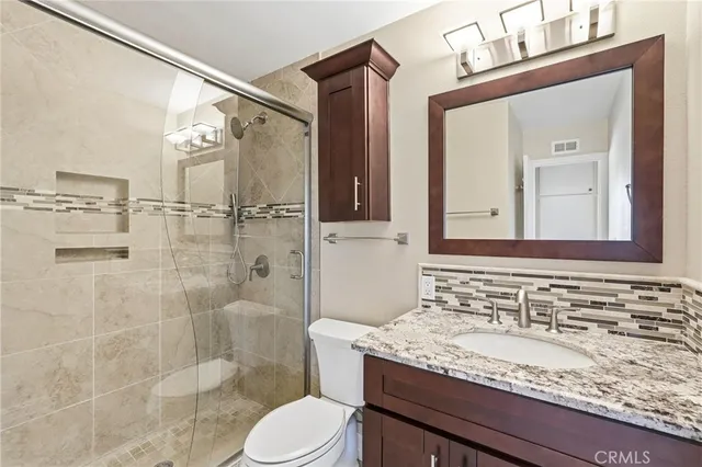 a bathroom with a granite countertop sink toilet a mirror and shower