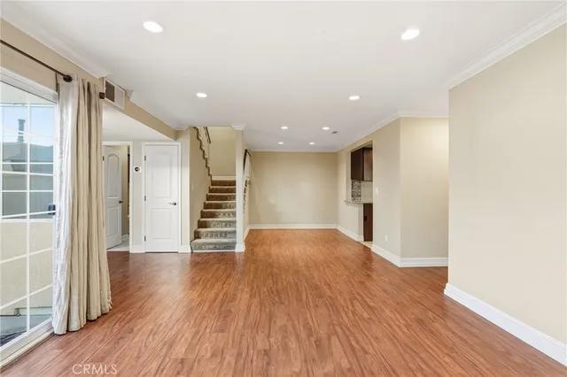 a view of a big room with wooden floor and windows