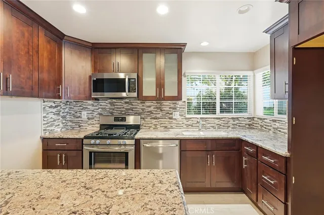 a kitchen with stainless steel appliances granite countertop wooden cabinets granite counter tops and a window
