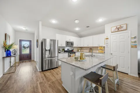 a kitchen with stainless steel appliances granite countertop a sink dishwasher stove refrigerator and microwave with wooden floor