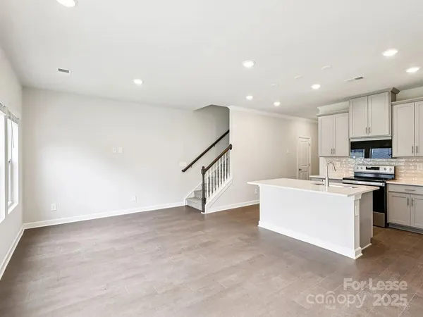 a view of kitchen with stainless steel appliances granite countertop a stove top oven a sink and dishwasher with wooden floor