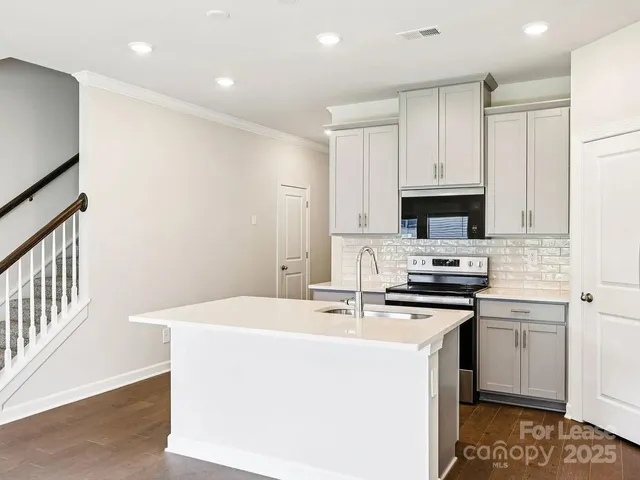 a kitchen with stainless steel appliances a sink a stove a microwave a center island and cabinets