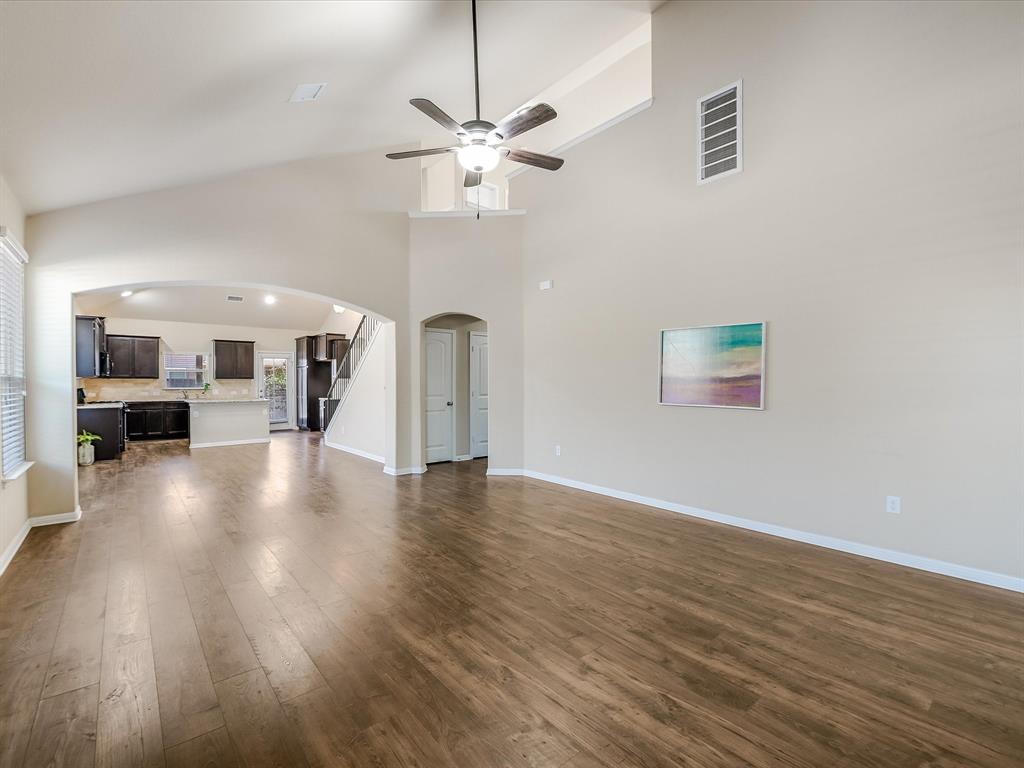 141 Serrano Street Georgetown, TX 78628 - Photo 2 of 7 A spacious common area boasts wood flooring, high ceilings, and a clear view to the kitchen.