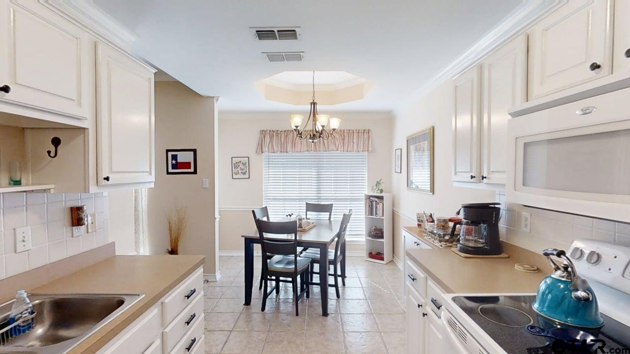 1202 Rice Road, Unit 143 Tyler, TX 75703 - Photo 11 of 27 a kitchen with a dining table chairs and white appliances