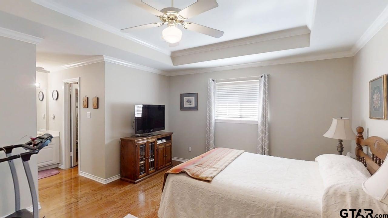 1202 Rice Road, Unit 143 Tyler, TX 75703 - Photo 13 of 27 a bedroom with a bed and a flat tv screen on the dresser