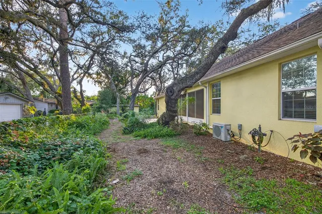 a backyard of a house with large trees and brick wall