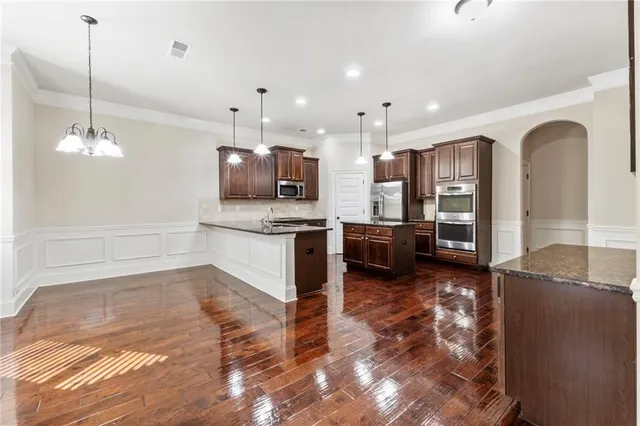 a large kitchen with granite countertop a large counter top stainless steel appliances and wooden floor