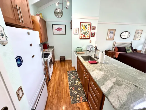 a kitchen with stainless steel appliances granite countertop a stove top oven a sink a dining table and chairs with wooden floor