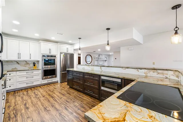 a kitchen with stainless steel appliances kitchen island granite countertop a refrigerator and a stove top oven