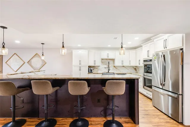 a kitchen with a sink a refrigerator and chairs