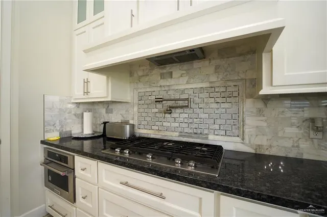 a kitchen with granite countertop a sink stainless steel appliances and cabinets