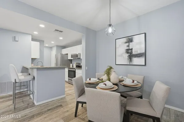 a kitchen with stainless steel appliances granite countertop a dining table chairs and view of living room