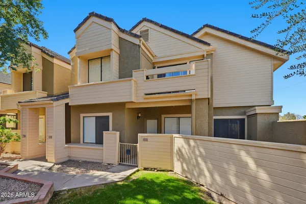 a view of a white house with a small yard and large tree