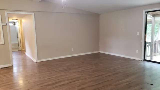 a view of an empty room with wooden floor and a window