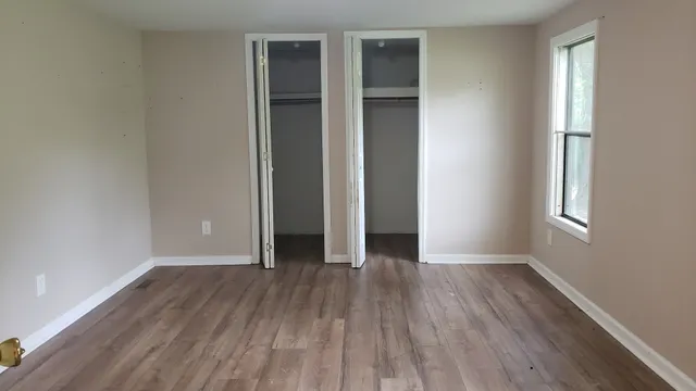 an empty room with wooden floor and windows