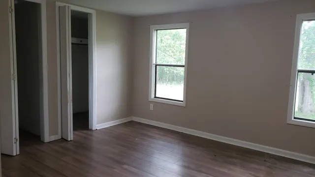 an empty room with wooden floor and windows