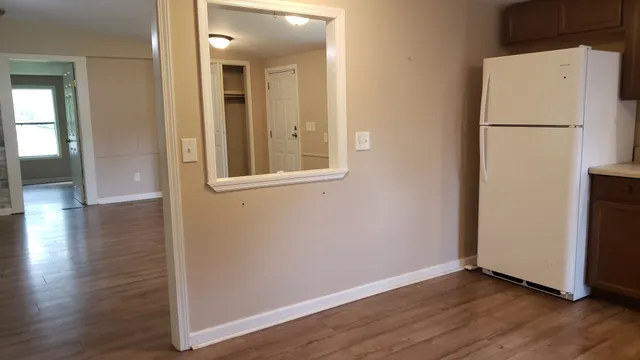 an empty room with wooden floor and mirror