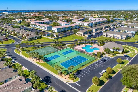 an aerial view of a tennis ground and a cars park side