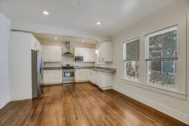 a large kitchen with white cabinets stainless steel appliances a window and a potted plant