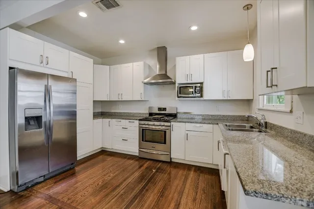 a kitchen with stainless steel appliances granite countertop a stove a sink and a refrigerator