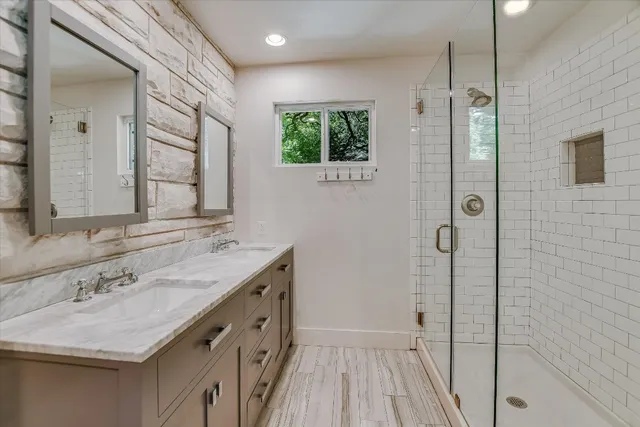 a bathroom with a sink a mirror a vanity and a shower