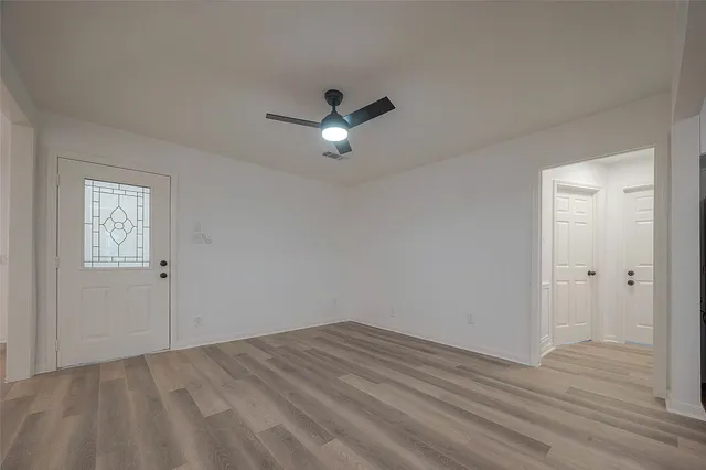 a view of empty room with wooden floor and ceiling fan