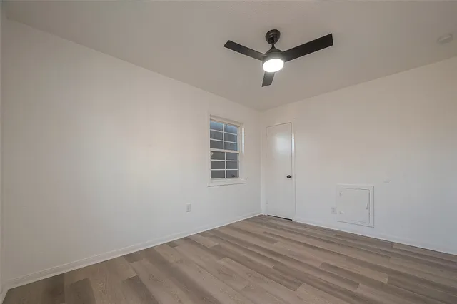 an empty room with wooden floor and ceiling fan