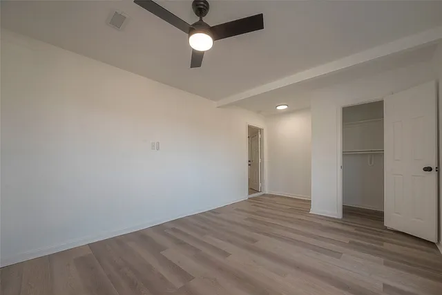 an empty room with wooden floor and ceiling fan