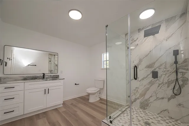 a bathroom with a granite countertop sink a toilet and shower